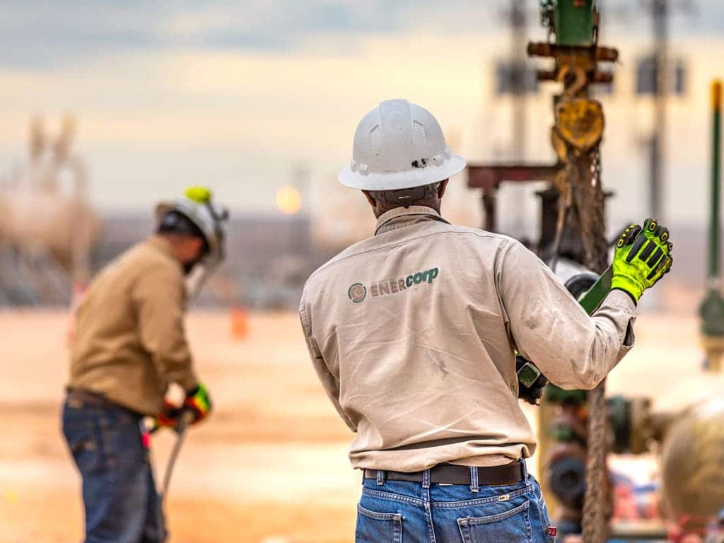 Two men working in the oil field for a sand management company